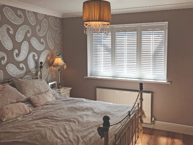 A bedroom with bed lights and window shutters