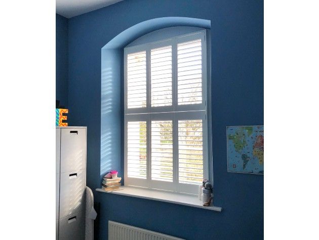 A blue bedroom wall with white window shutters