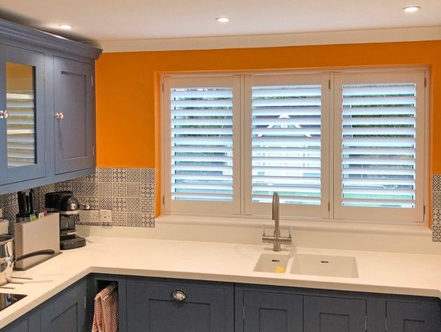 A kitchen with sink tap and window shutters