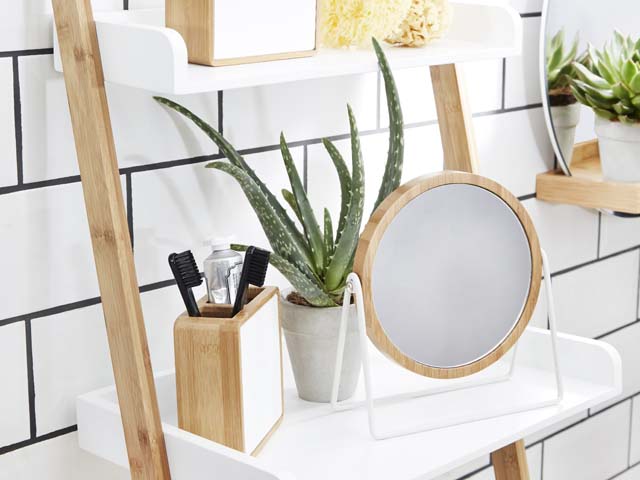 white shelving with aloe vera plant, mirror and other bathroom accessories in a bathroom with white metro tiles and dark black grouting 