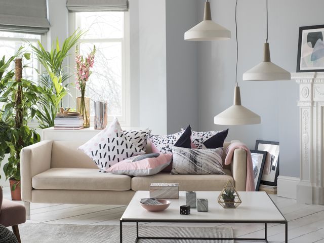 living room with statement lighting, a cream plush sofa with a range fo colourful cushions, homeware on coffee table, a collection of green plants by bhs spring summer 2018