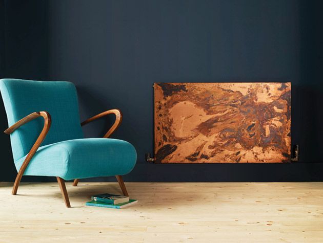 bisque etched copper radiator in living room with navy walls wooden flooring and a turquoise arm chair