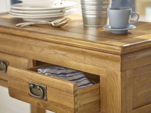 french farmhouse trend wood console table by oak furnitureland with a cup, metal planter and dinnerware on top