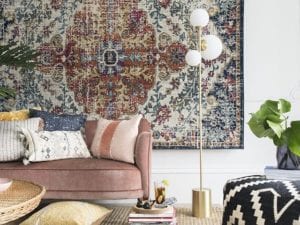 pink velvet sofa with a collection of cushions and a moroccan style rug on wall by bhs ss18 spring summer 2018