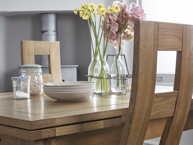 rustic dining set table and chairs by oak furnitureland with a vase of flowers and dinnerware on top