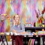 interior designer sophie robinson smiling at desk with a colourful background