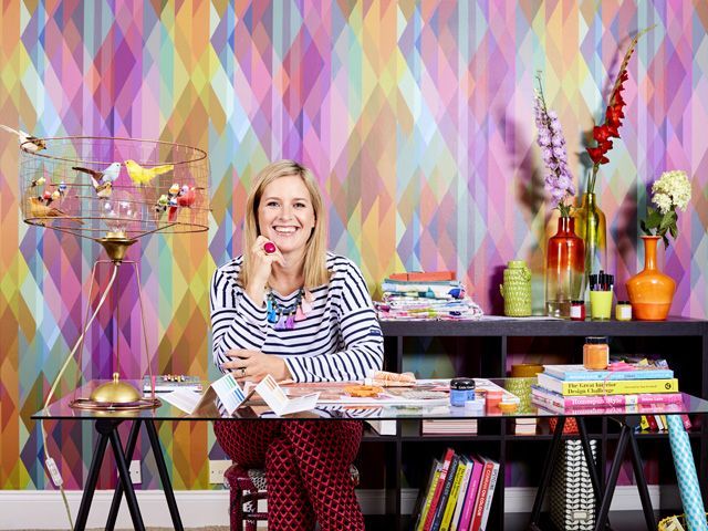 interior designer sophie robinson smiling at desk with a colourful background 