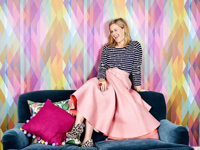 sophie robinson on back of a velvet sofa winking in front of a coloured background