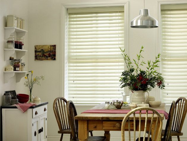 white faux wood venetian blinds in white kitchen with wooden dining table and chairs