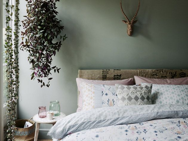 botanical bedroom with green walls and stag wall hanging
