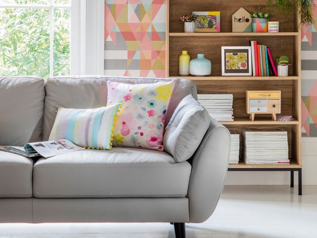 scandi style sofa, colourful geometric wallpaper and wooden bookshelf in a living room by tesco ss18 capri home collection 