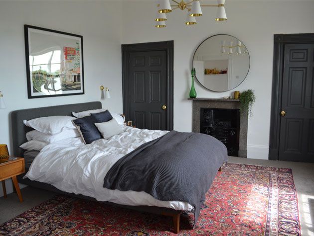 grey and white bedroom interior with persian rug under bed