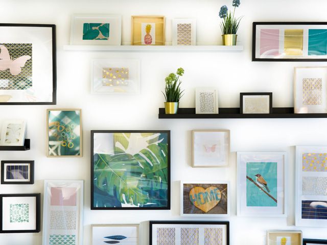 A gallery wall with organised storage, plants and picture frames and artwork