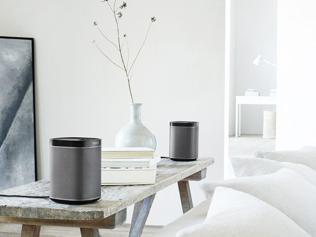 two sonos play1 speaker system on a side table in a light, bright living room