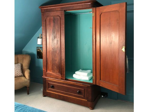 large wooden antique wardrobe in teal scheme bedroom