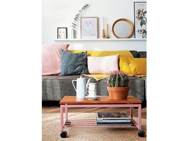 white scheme living room with grey sofa pink and yellow cushions cactus on coffee tabel