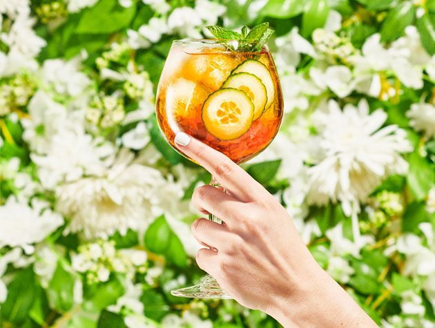 womans hand holiding up a glass of pimms copy