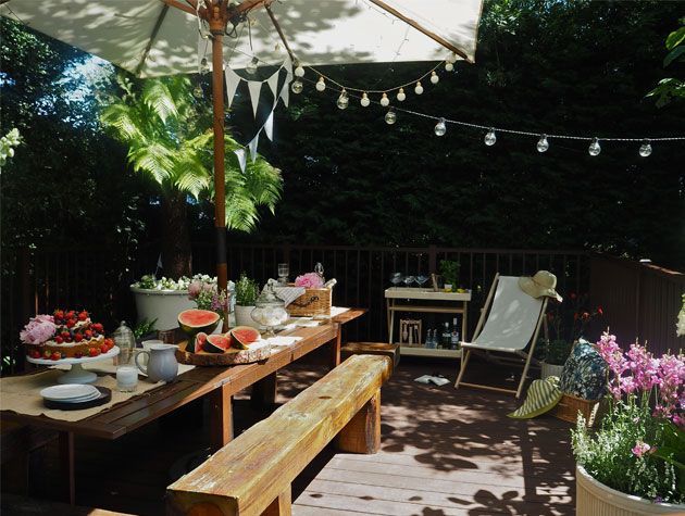 garden decking with wooden garden table decorated with flowers cake and fruit