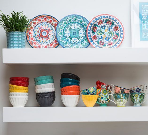 mexican style hand painted plates with green plant in blue plant pot on white wall shelf