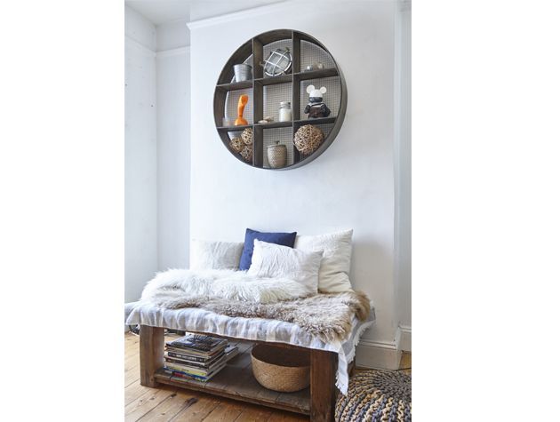 bed layered with shagpile rugs cushions and a circle shelf above the bed