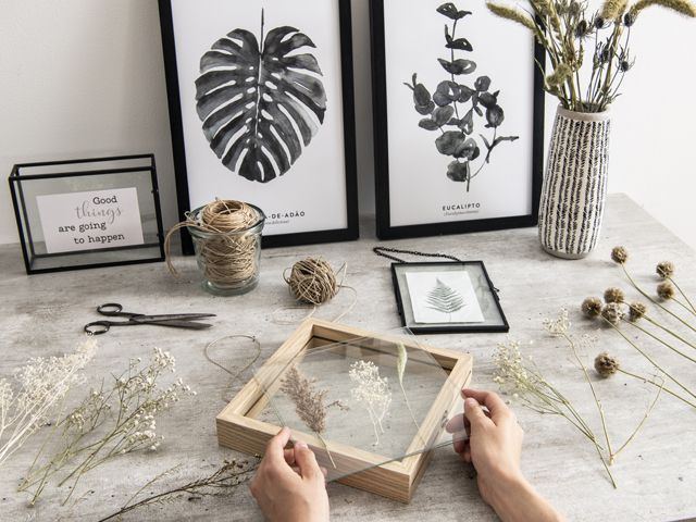 a womans hands holding a picture frame on a table with wildflowers from aw18 maison du monde - living room - goodhomesmagazine.com