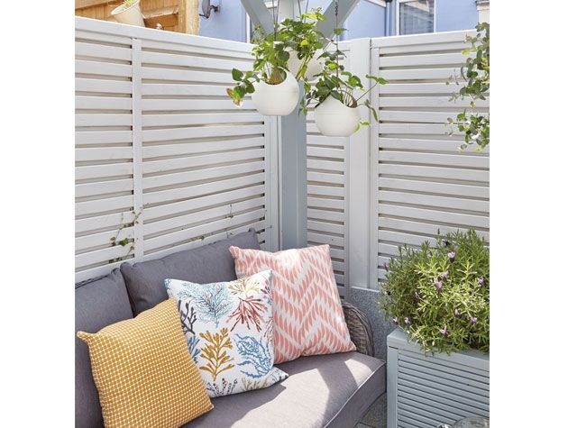 Secluded garden area with grey sofa and hanging plants - garden-goodhomesmagazine.com