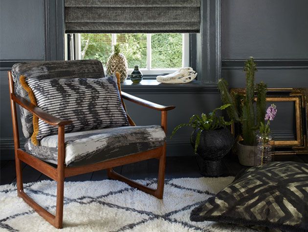 Wooden arm chair with grey patterned cushion with fringing in grey living room from the Abigail Ahern and Hillarys collection -living-room-goodhomesmagazine.com