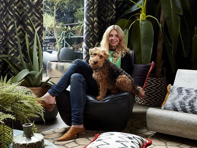 Interior designer Abigail Ahern with her dog on a seat in a living room with her Hillarys blinds and curtains in the background