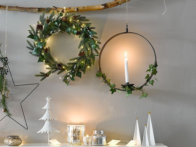 christmas wreaths with fresh foliage and greenery hanging over a mantelpiece with a sturdy branch