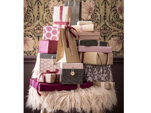 Christmas presents stacked on a chair wrapped in pink and gold Christmas wrapping paper -maisons-du-monde-living-room-goodhomesmagazine.com