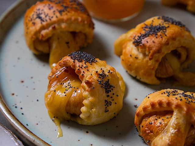 Figs enclosed in pastry with poppyseeds on top served on grey dish