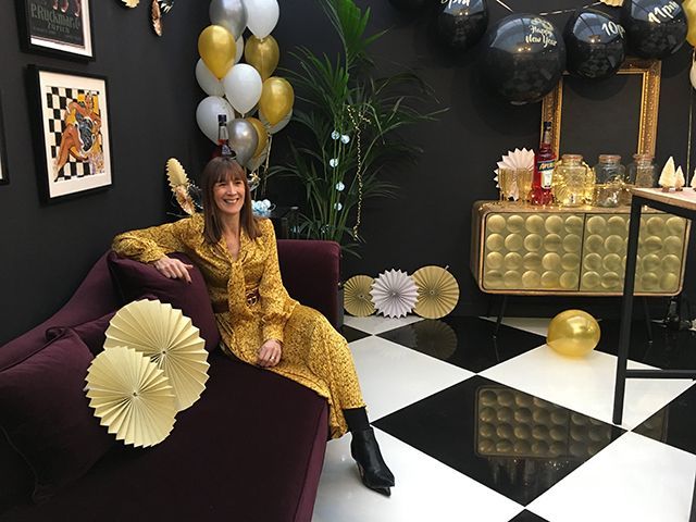 Karen Walker, editor of Good Homes Magazine, sitting on a purple chaise sofa at the Disco themed Good Homes Roomset Ideal Home Show Xmas 2018 - Roomsets - goodhomesmagazine.com