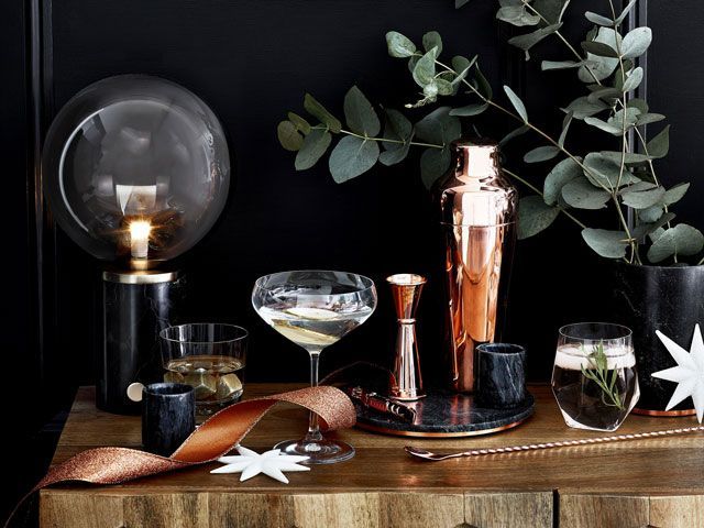 copper-barware-on-a-wooden-sideboard-with-vase-of-eucalyptus