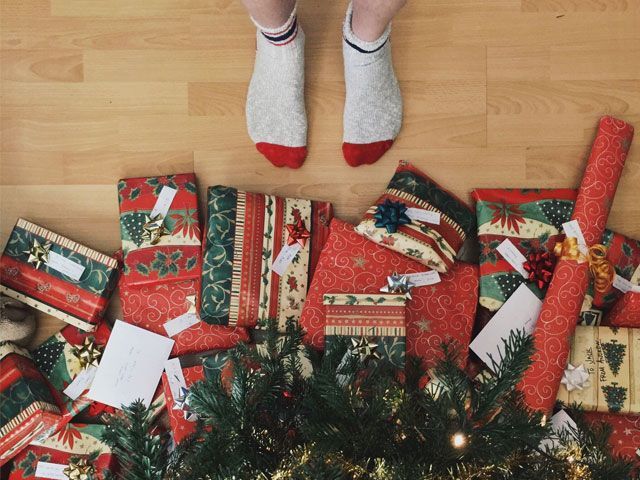 Man's feet at Christmas tree with presents -unsplash-shopping-goodhomesmagazine.com