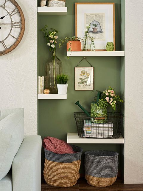 Fireplace alcove with white floating shelving against a forest green wall