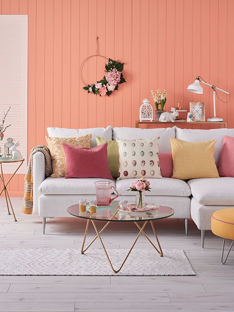 Coral panelling in a Easter-themed living room with neutral sofa and pink and yellow cushions