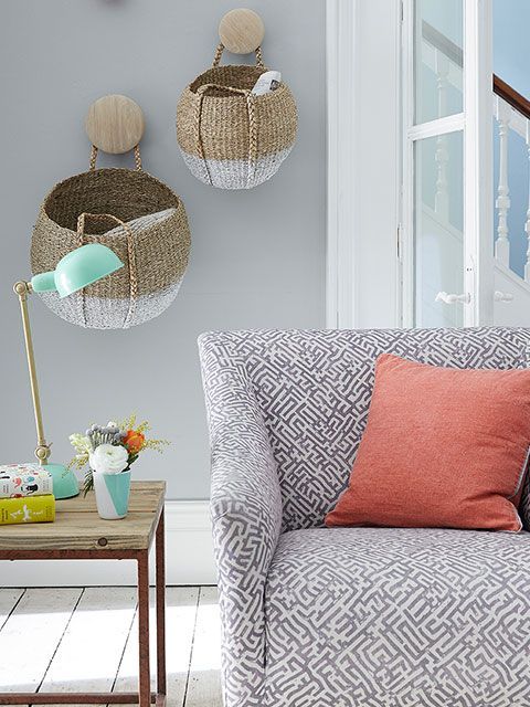 A grey modern living room with woven baskets hanging from the wall as extra storage