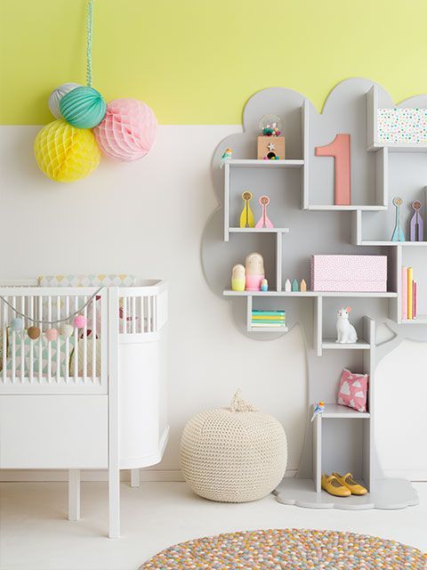 Scandi style nursery with yellow and white wall, modern crib and tree-shaped grey shelving