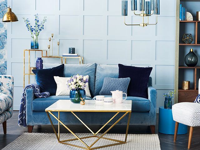 Blue panelling with velvet blue sofa, brass accents and shades of blue cushions