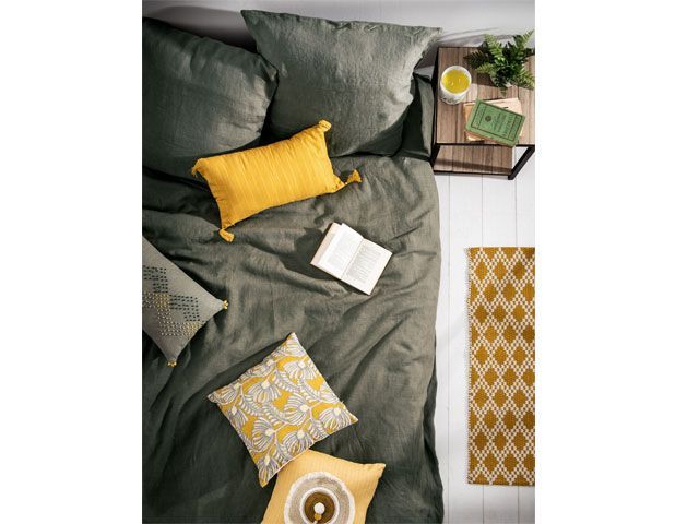Maisons du Monde's SS19 Paper Shop trend showcased in bedroom with grey bedding and yellow cushions scattered across the bed -maisons-du-monde-living-room-goodhomesmagazine.com