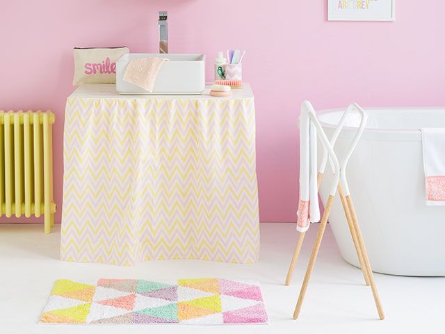 Modern bathroom with pink walls, geometric accessories, yellow traditional radiator and under-sink curtain