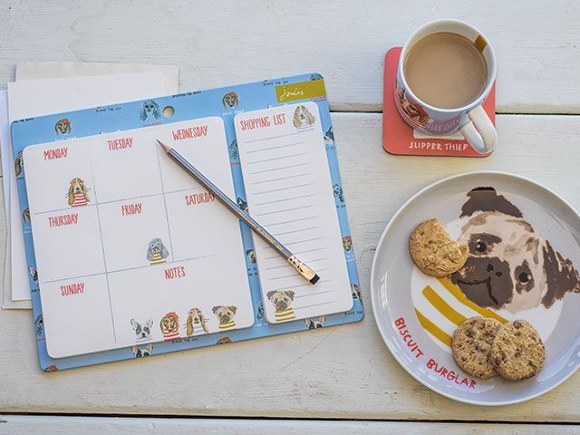 Dog-themed weekly planner on a table with a mug and plate alongside, both with dog designs