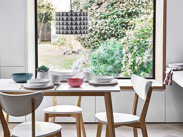 A Scandi-style white dining area, looking out to the garden via a big picture window