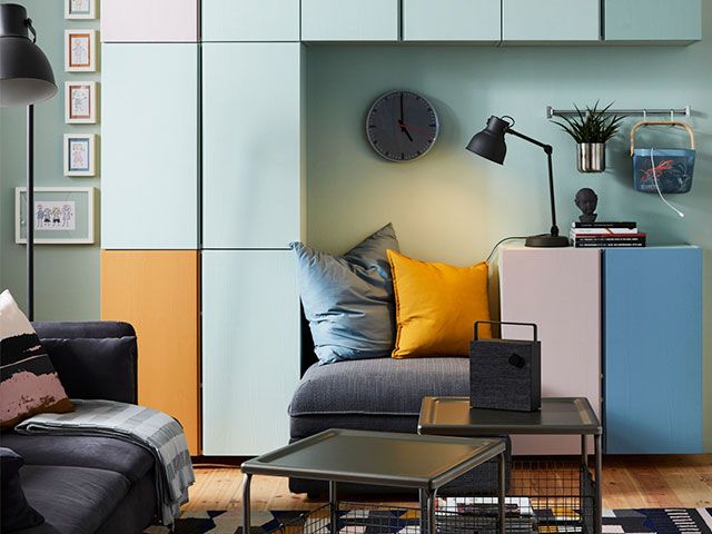A living room with a wall of modular rectangular storage, painted blue, orange and pink