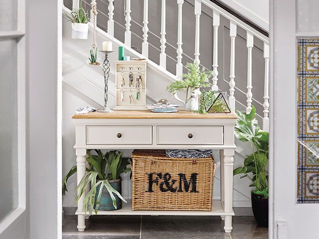 White, modern country-style hallway console dressed with lots of plants