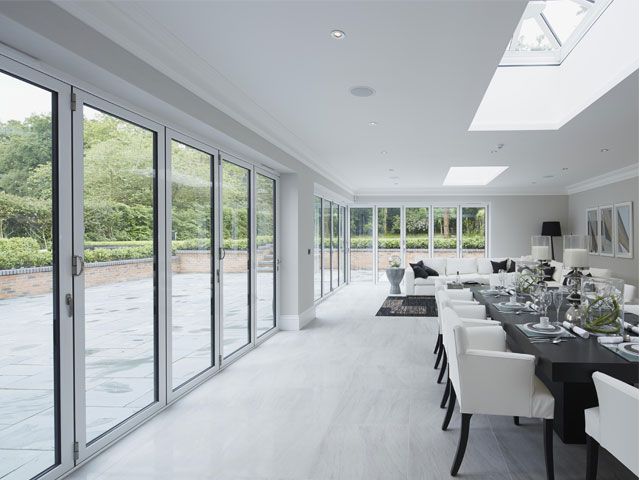 A dining room with Bi-fold doors, a black dining table and white dining chairs -origin-living-room-goodhomesmagazine.com