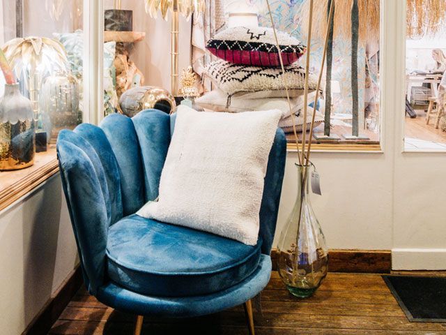 blue velvet chair with lighting and a tower of cushions