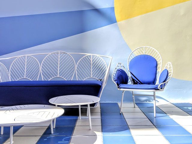 blue and yellow walls with white outdoor furniture and blue cushions