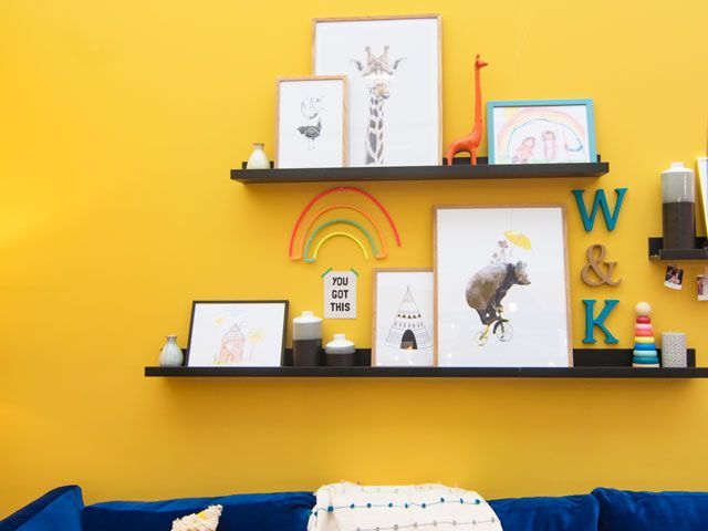 Crown Mustard Jar yellow paint on walls with wall art on shelving in the family living space in the good homes roomsets at Ideal Home Show 2019