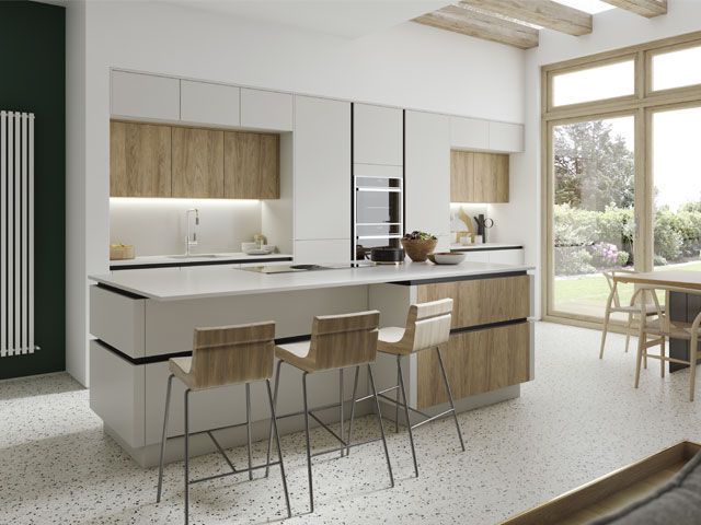 A white fitted kitchen with breakfast bar and wooden chairs -masterclass-kitchens-kitchens-goodhomesmagazine.com
